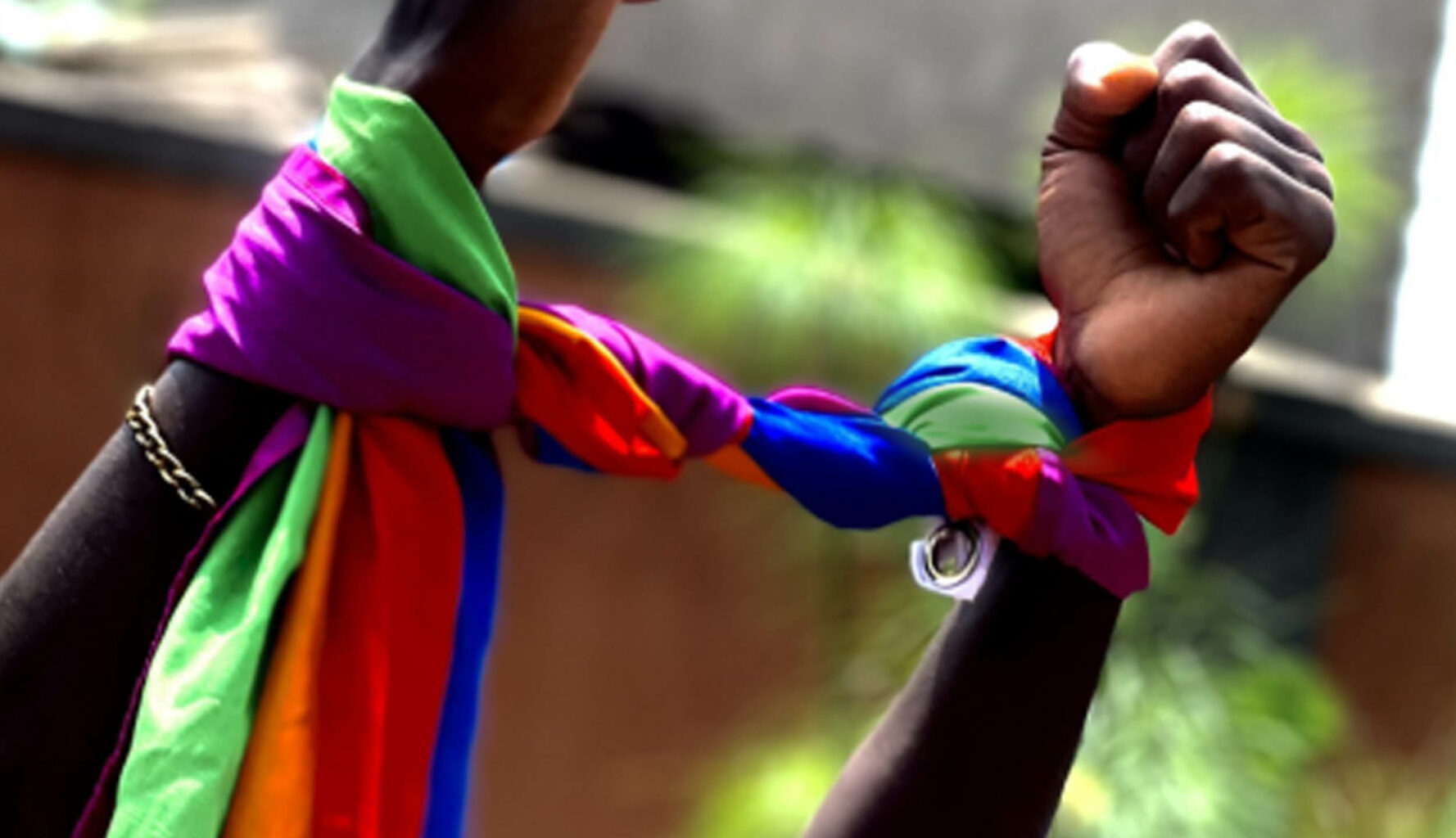 Header Queer Emergency Aid Alliance Uganda - hands with a rainbow flag